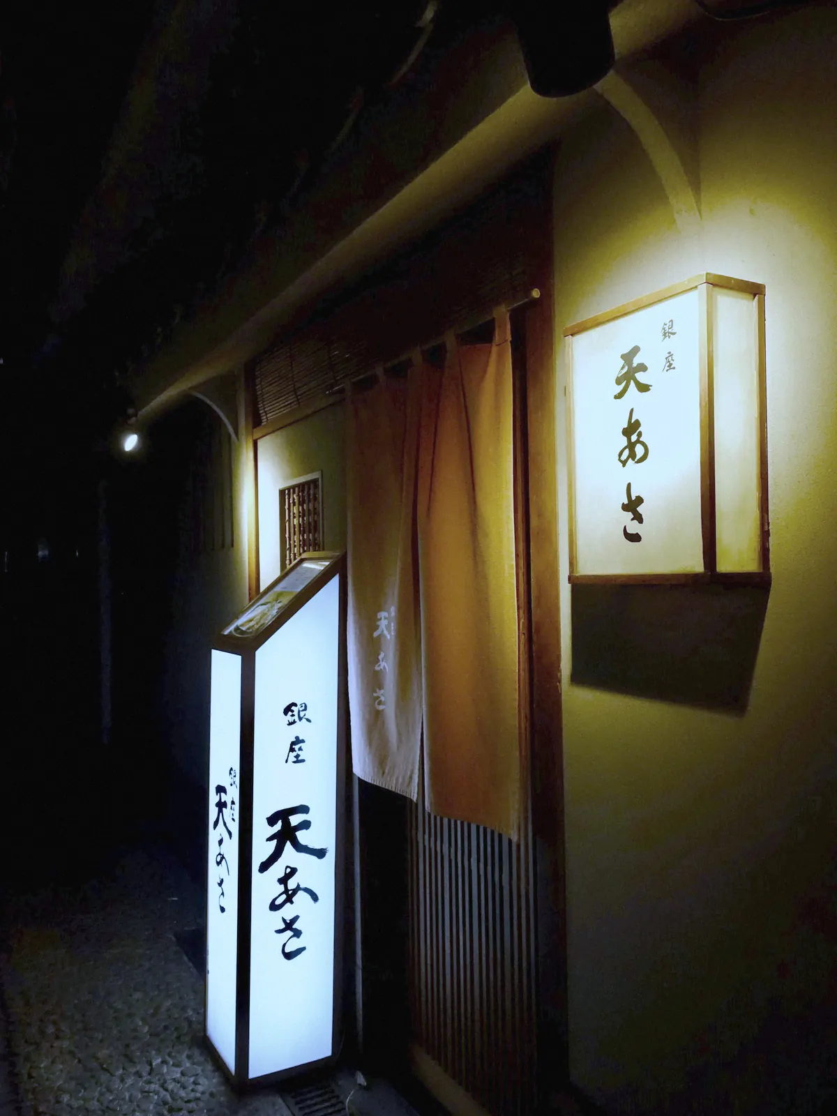 夜の入口。木の戸のわきに小さな灯りがともる